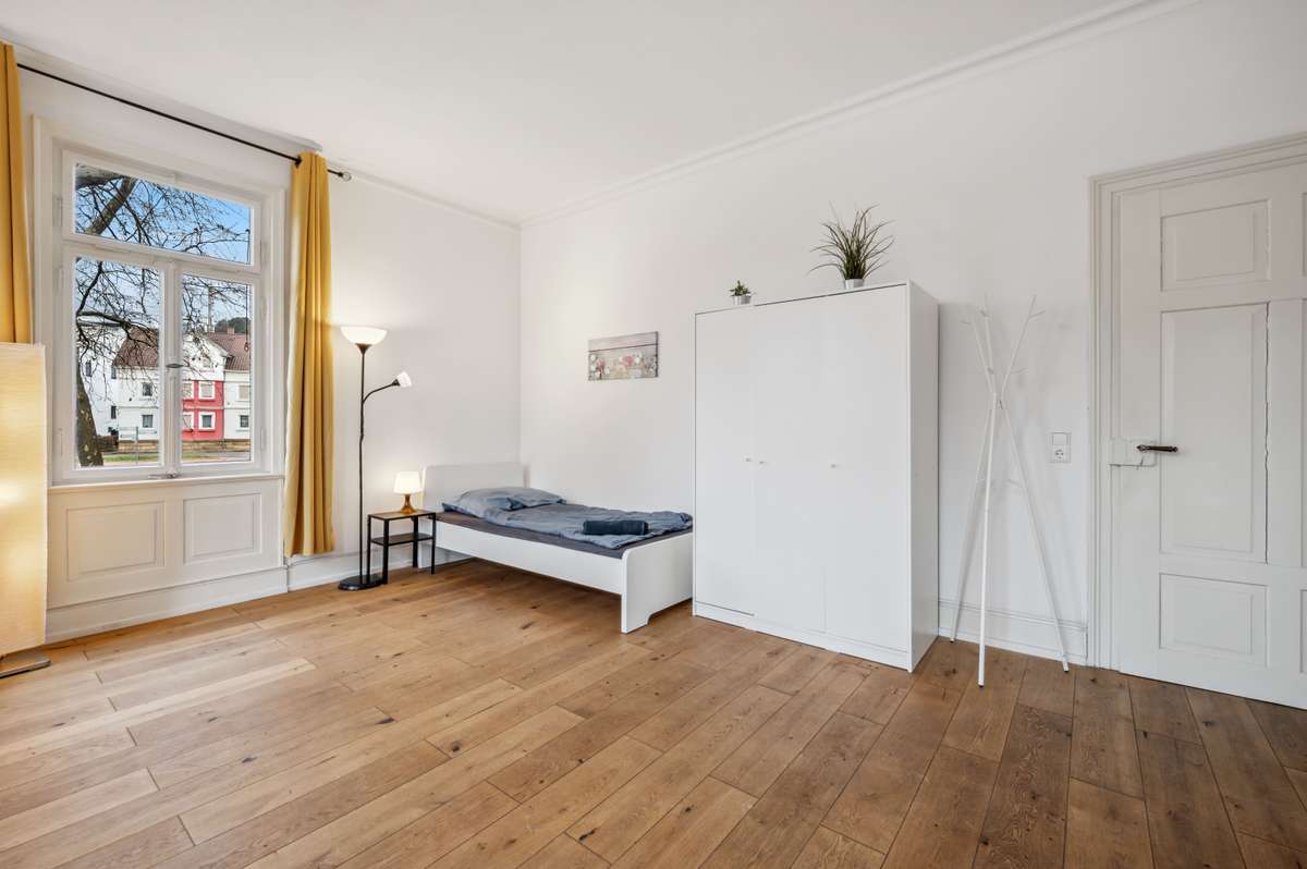 Schlafzimmer mit hohen Altbaufenstern im Haus Silcherstraße 13